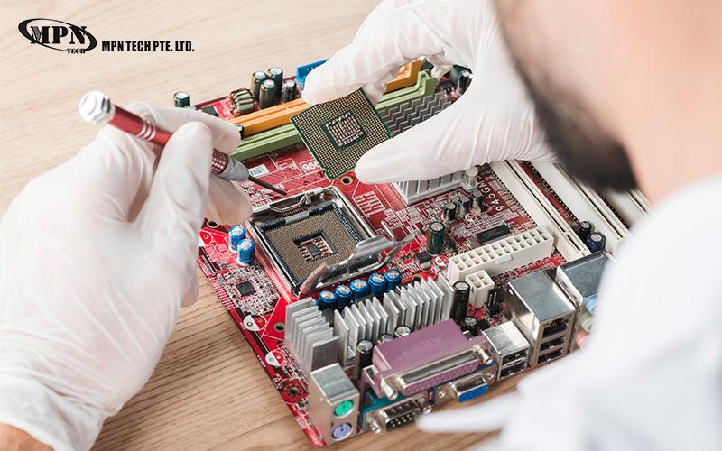 A technician in white gloves installing a CPU processor into a red motherboard using a precision screwdriver.