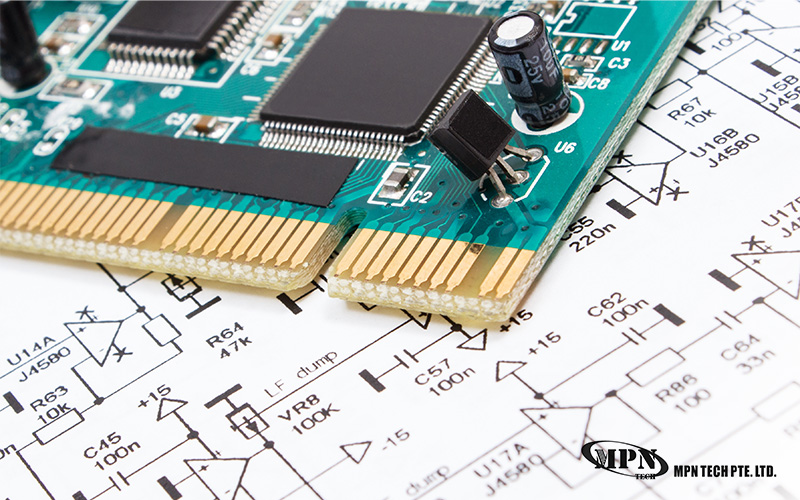 A close-up of an electronic circuit board showing components like transistors and capacitors resting on a technical schematic.