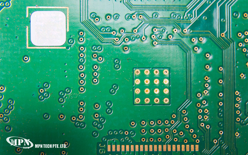 Macro close-up of a green PCB surface showing copper traces and solder points.