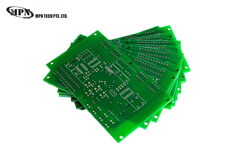 Stacked green PCBs showing precise circuit trace routing.