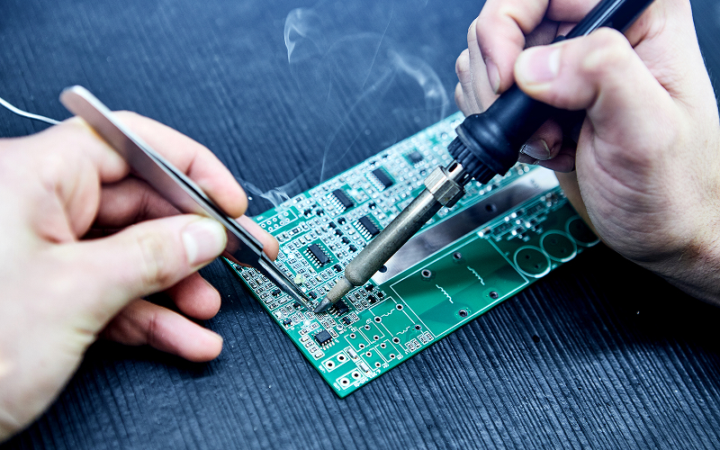 Technician-soldering-components-onto-printed-circuit-board-assembly