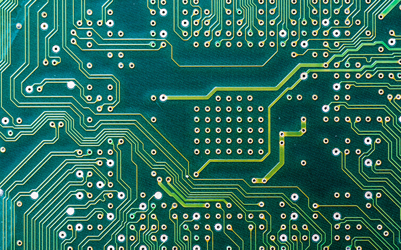 Detailed view of PCB routing copper traces on green circuit board.