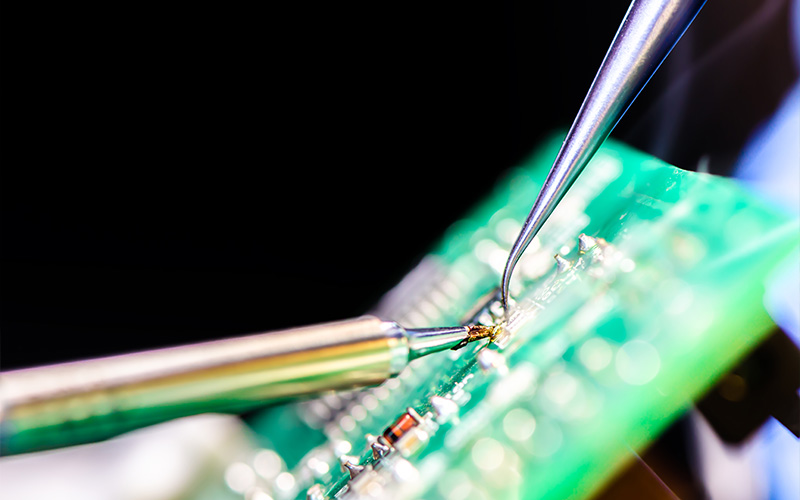 close-up of precision soldering iron working on pcb components