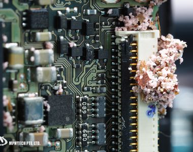 A macro view of an electronic circuit board showing significant pink crystalline corrosion or debris around a connector.