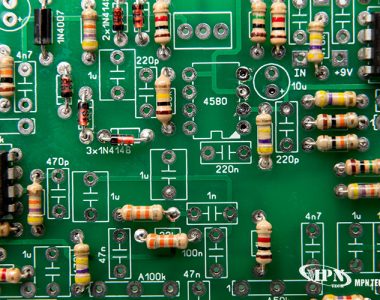 Close-up of green printed circuit board with labeled resistors, capacitors, diodes, and integrated circuits.